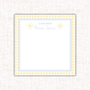 May include: A square notepad with a yellow and white gingham border and a light blue inner border. The top of the notepad has the text "A NOTE FROM Mrs. Lori" with sun illustrations on either side.