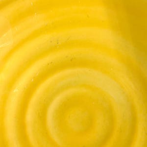 K&ouml;nnte beinhalten: Nahaufnahme einer gelben Keramikschale mit konzentrischen Kreismustern. Die Schale hat eine glatte, gl&auml;nzende Oberfl&auml;che.