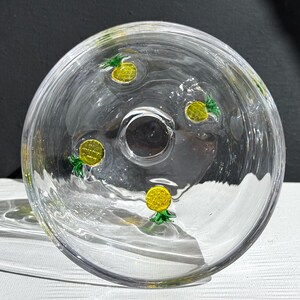 May include: Clear glass bowl with a central hole and decorative yellow and green pineapple designs. The bowl is round and has a slightly curved shape, with the pineapple designs evenly spaced around the interior.