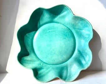May include: A teal green ceramic serving bowl with a scalloped edge. The bowl is made of glazed pottery and has a rustic, handmade look.