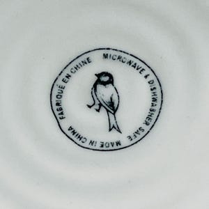 K&ouml;nnte beinhalten: Ein wei&szlig;er Keramikteller mit einer Schwarzwei&szlig;-Vogel-Illustration und dem Text "Made in China, Mikrowellen- und Sp&uuml;lmaschinenfest, Fabriqu&eacute; en Chine".