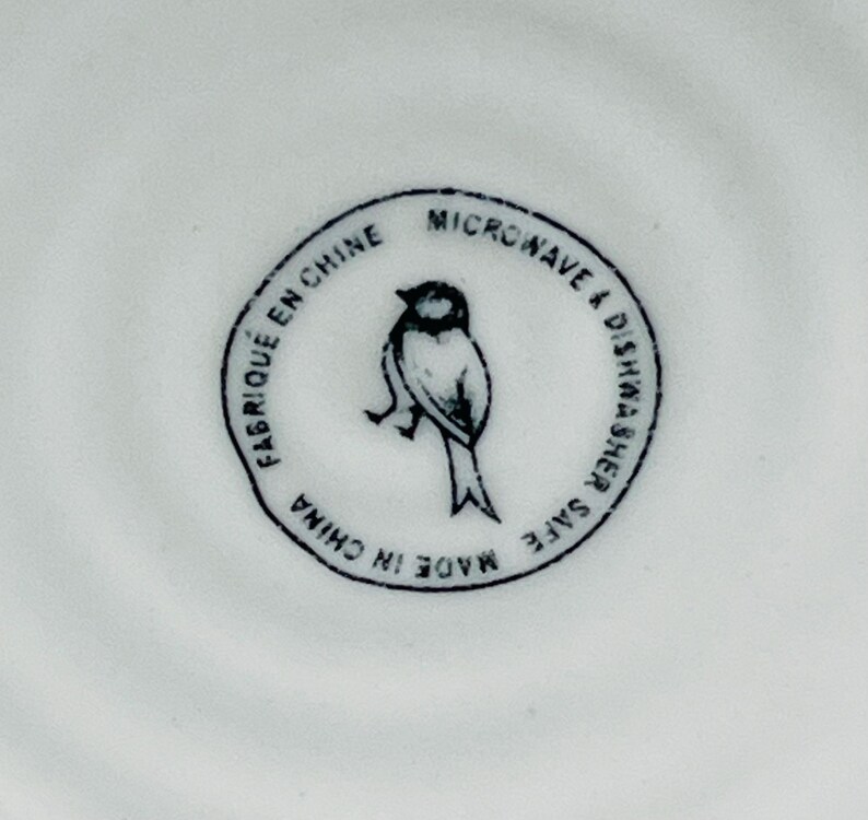 K&ouml;nnte beinhalten: Ein wei&szlig;er Keramikteller mit einer Schwarzwei&szlig;-Vogel-Illustration und dem Text "Made in China, Mikrowellen- und Sp&uuml;lmaschinenfest, Fabriqu&eacute; en Chine".