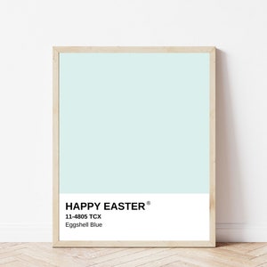 Puede incluir: Un póster enmarcado con un fondo azul claro y las palabras "HAPPY EASTER" en texto negro. Debajo, el código de color "11-4805 TCX" y el nombre del color "Eggshell Blue". El marco es de color madera clara.