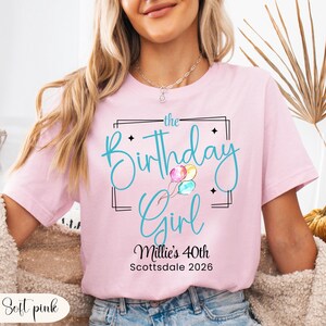 Puede incluir: Camiseta rosa claro con la frase "the Birthday Girl" en turquesa, con globos. Debajo, se lee "Millie's 40th Scottsdale 2026". La camiseta es de color rosa claro.