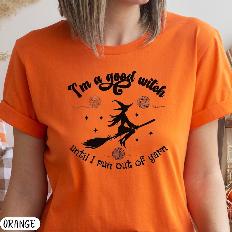 Funny Halloween knitting lovers t-shirt adorned with a silhouette of a witch riding a broom surrounded by stars and balls of yarn, and the phrase, "I'm a good witch until I run out of yarn". Bella and Canvas 3001 crew neck t-shirt.