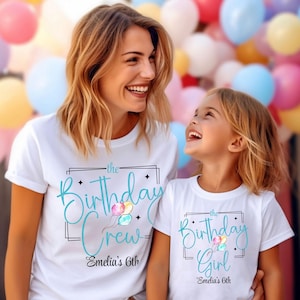 Puede incluir: Dos camisetas blancas con dise&ntilde;os a juego. Una dice "the Birthday Crew" y la otra "the Birthday Girl" en escritura turquesa, con globos y el nombre "Emelia's 6th". El fondo es una colorida variedad de globos.