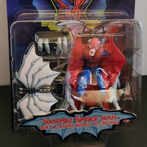 May include: A plastic package containing a red and blue action figure of Spider-Man with bat wings. The figure is labeled "Vampire Spider-Man" and "Bat Launching Action!" The package also includes a white bat with a black spider on it.