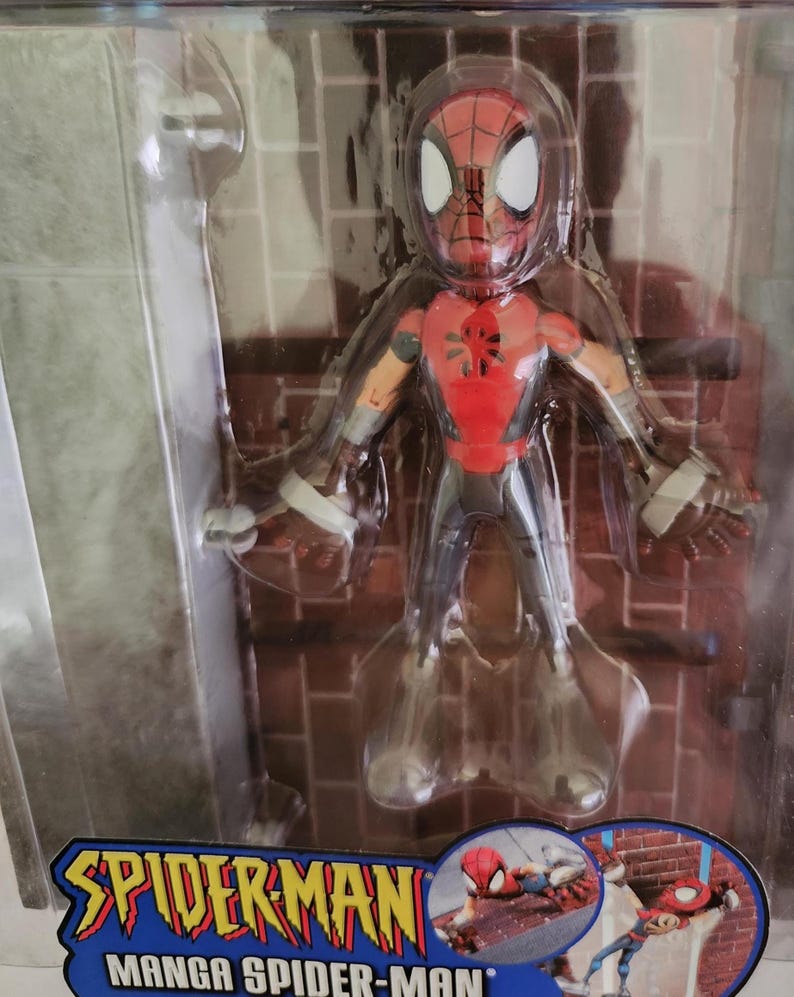 Peut inclure: Une figurine d'action rouge et noire de Spider-Man dans un style manga. La figurine est pos&eacute;e les bras tendus et se tient debout sur un mur de briques. L'emballage comprend le texte "Spider-Man Manga Spider-Man".
