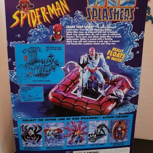 May include: A Spider-Man Web Splashers action figure, packaged on a purple and blue background. The figure is on a red raft, with the words "Web Splashers" and "Spider-Man" prominently displayed. The packaging includes text describing the figure's features.