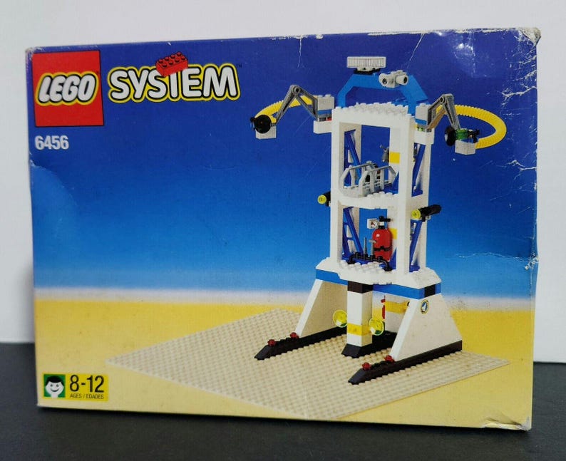 Puede incluir: Un set de Lego System con una estaci&oacute;n espacial blanca y azul con un brazo de gr&uacute;a amarillo. La caja es azul y blanca con el logotipo de Lego System y el n&uacute;mero de set 6456. La caja tambi&eacute;n dice 8-12 a&ntilde;os.