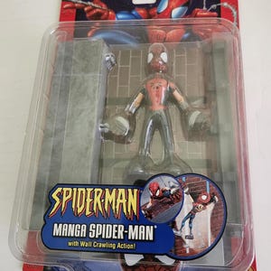 Peut inclure: Une figurine d'action Spider-Man rouge et noire avec une action de grimper aux murs. La figurine est dans un emballage en plastique avec une toile de fond de mur de briques gris. L'emballage pr&eacute;sente &eacute;galement une image rapproch&eacute;e de Spider-Man grimpant sur un mur de briques.