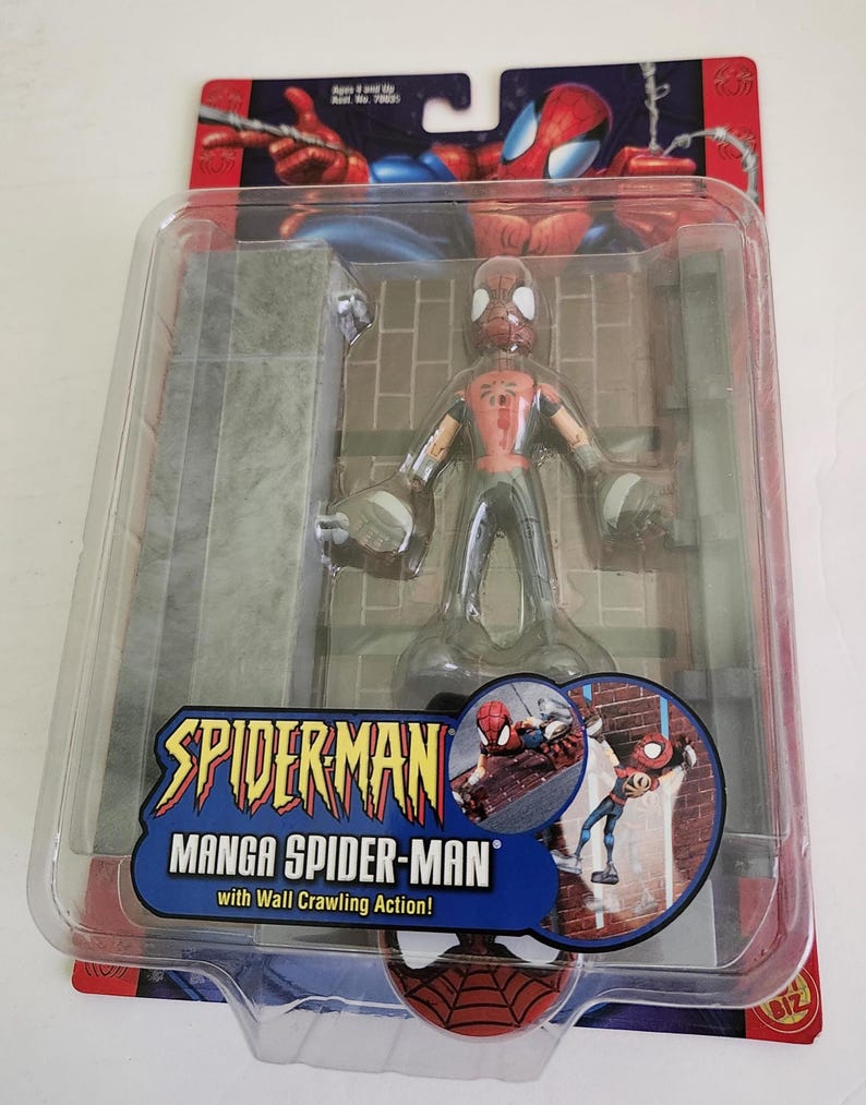 Peut inclure: Une figurine d'action Spider-Man rouge et noire avec une action de grimper aux murs. La figurine est dans un emballage en plastique avec une toile de fond de mur de briques gris. L'emballage pr&eacute;sente &eacute;galement une image rapproch&eacute;e de Spider-Man grimpant sur un mur de briques.
