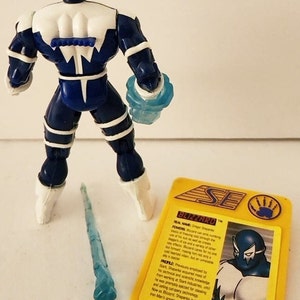 Op de afbeelding: Een blauwe en witte action figure van Blizzard, een superheld uit het Marvel-universum. De figuur houdt een blauw ijswapen vast. De figuur staat op een wit oppervlak. De kaart op de achtergrond heeft de naam van het personage en zijn krachten.