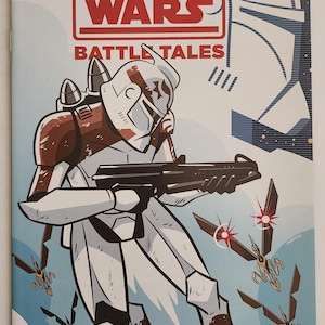 May include: Comic book cover for Star Wars Adventures: The Clone Wars. The cover features a white and brown armored character holding a blaster, with the title "The Clone Wars" in red and white. The background is light blue with flying vehicles.