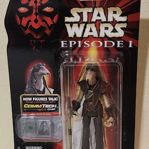 Könnte beinhalten: Star Wars Episode I Actionfigur von Captain Tarpals mit Elektrostab. Die Figur befindet sich in einer transparenten Kunststoffhülle mit einem schwarzen und roten Hintergrund mit Darth Maul und dem Star Wars-Logo. Die Verpackung enthält den Text "CommTech Chip".
