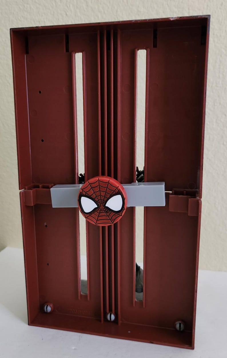 Peut inclure: Bo&icirc;te de rangement rouge et noire sur le th&egrave;me de Spider-Man. La bo&icirc;te a une conception &agrave; charni&egrave;re avec un embl&egrave;me Spider-Man sur le devant. La bo&icirc;te est en plastique et de forme rectangulaire.