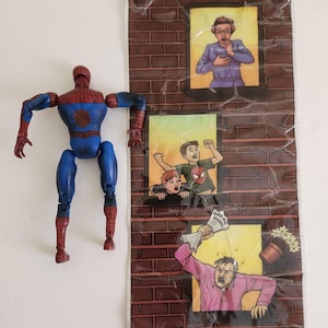 May include: A blue and red Spider-Man action figure stands next to a brick wall backdrop with three illustrated window scenes. The scenes depict people reacting to something, with one holding a newspaper that reads "Spider-Man Menace."