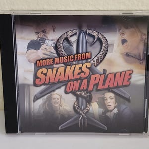 以下が含まれることがあります： 映画「Snakes on a Plane」のタイトルが記載されたCDケース。カバーアートには俳優の画像と「More Music From Snakes on a Plane」の文字が描かれています。CDケースは透明で、背表紙は黒色です。
