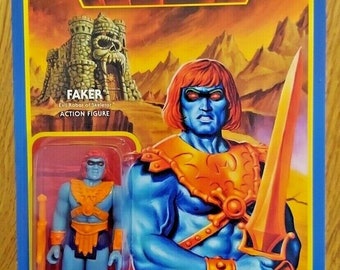 May include: A Masters of the Universe action figure of Faker, the Evil Robot of Skeletor. The figure is blue with orange accents and is holding a sword. The figure is packaged in a plastic blister pack with a cardboard backing. The packaging features a cartoon image of Faker with a red and orange color scheme.