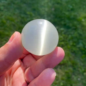 May include: A white, smooth, round, polished selenite crystal ball.