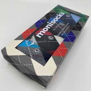 May include: A box of colourful argyle socks in a gift box with a window showing the socks. The box is grey with a diamond pattern and the text "monisocks Est. 1964" and "COLORFUL ARGYLE BOXES EUR SOCK SIZE 40-45".