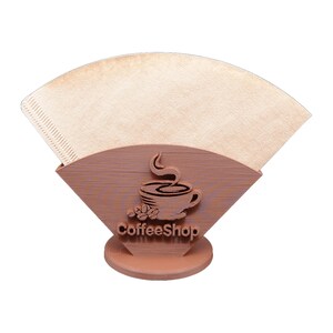 Può includere: Un portafiltro per caffè in legno marrone con un disegno di tazza di caffè e la scritta "CoffeeShop". Il supporto contiene un filtro di carta per caffè. Il supporto è su una base rotonda.