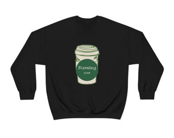 Op de afbeelding: Zwart sweatshirt met een groene en witte illustratie van een koffiebeker met de tekst "Nursing Elixir" op een groene cirkel.