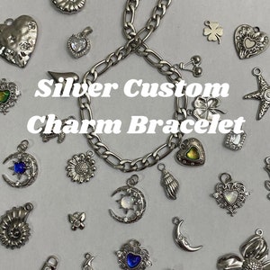 Peut inclure: Un bracelet à breloques argenté avec divers charms, dont des cœurs, des lunes, des fleurs et des coquillages. Les breloques sont dispersées autour du bracelet, avec le texte "Silver Custom Charm Bracelet" au centre.