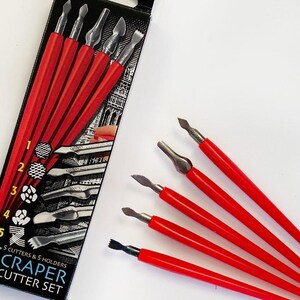 Könnte beinhalten: Ein Schabermesserset mit fünf Messern und fünf Haltern. Die Messer haben silberne Klingen und leuchtend rote Griffe. Die Verpackung zeigt die Messer und ihre entsprechenden Muster. Der Text "SCRAPER CUTTER SET" ist sichtbar.