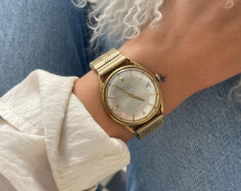 Reloj de pulsera unisex de vestir grueso de Avia Olympic, estilo suizo vintage de los años 70, con 17 joyas, mecanismo Incabloc, cuerda manual, caja redonda chapada en oro y correa elástica.