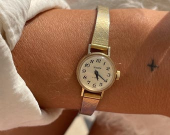 Montre-bracelet vintage chic des années 1970 pour femme, à remontage mécanique, avec bracelet fin côtelé doré et cadran rond doré, signée Sekonda.