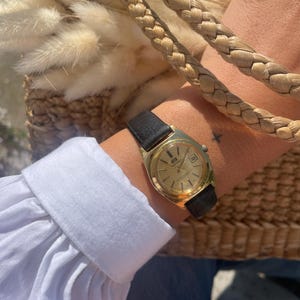 Vintage 1980s Automatic Gold Tone Round Bezel Manual Wind Up Black Leather Strap Ladies Everyday Wristwatch By Seafarer