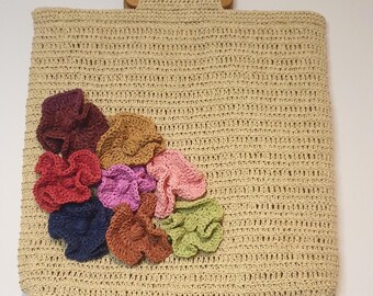 May include: A beige crocheted tote bag with a wooden handle and colorful crocheted flowers on the front.