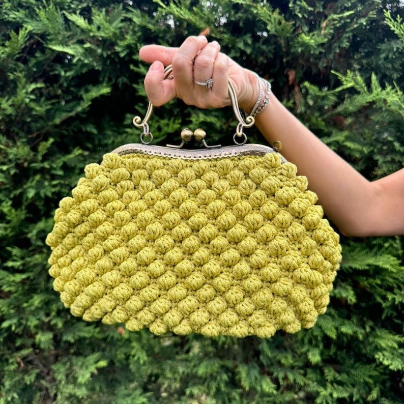 May include: A bright yellow crocheted purse with a vintage-style metal clasp and handle.