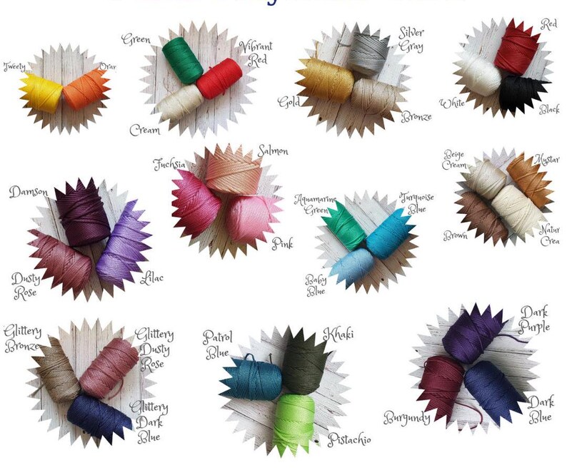 May include: Assortment of colorful embroidery floss spools arranged in a circular pattern on a wooden surface. Each spool is labeled with a color name, such as "Green", "Vibrant Red", "Cream", "Salmon", "Pink", "Aquamarine Green", "Turquoise Blue", "Dusty Rose", "Lilac", "Baby Blue", "Glittery Bronze", "Glittery Dusty Rose", "Patrol Blue", "Khaki", "Pistachio", "Burgundy", "Dark Purple", "Dark Blue", "Damson", "Beige Cream", "Mystar", "Natur Crea", "Silver Gray", "Gold", "Bronze", "White", "Black", "Twerly", "Juchsia", "and "Glittery Dark Blue".