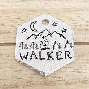 Op de afbeelding: Zilveren zeshoekige huisdiertag met een ontwerp van een kampvuur, bergen, sterren en een halve maan. De tekst "WALKER" is onder het ontwerp gegraveerd.