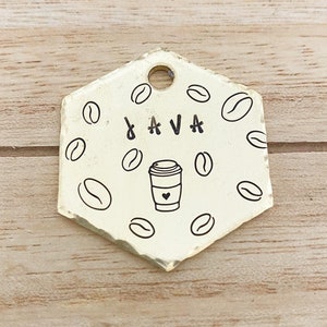 May include: Gold hexagonal dog tag with a coffee cup and the word "JAVA" engraved on it. The tag is decorated with a pattern of coffee beans.