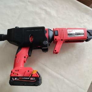 Puede incluir: Un taladro inal&aacute;mbrico rojo y negro con una funda de transporte negra y una bater&iacute;a de iones de litio roja. El taladro est&aacute; etiquetado como "Milwaukee M18 FUEL" y "RED LITHIUM M18".