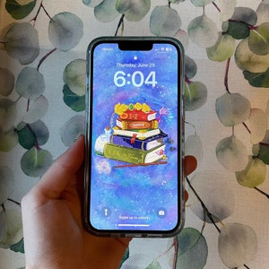 May include: A smartphone with a blue and purple galaxy background. The screen displays the time 6:04 and the date Thursday, June 29. A stack of books with a wand and a potion bottle are on the screen. The text "Swipe up to unlock" is at the bottom of the screen.