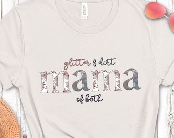 以下が含まれることがあります： 花柄のデザインと「glitter & dirt mama of both」という文字がプリントされた白いTシャツです。