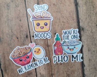 May include: A collection of colorful stickers featuring cartoon illustrations of Asian-inspired food items. The stickers include bowls of noodles, eggs, and bottles of sauce, with phrases like "Send Noods" and "We Ramen to Be."