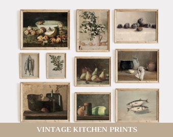 May include: A collection of nine vintage kitchen prints in wooden frames. The prints feature still life images of fruit, vegetables, fish, and kitchenware. The prints are arranged in a grid pattern on a white wall.