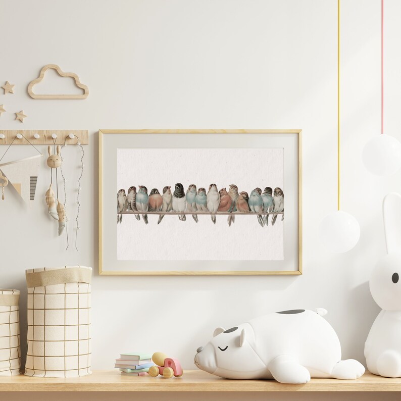 May include: A framed watercolor print features a row of colorful birds perched on a wire. The birds display a variety of colors, including blue, red, and black. The artwork is set against a neutral background, and the frame is a light wood color.