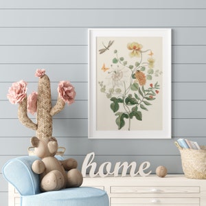 May include: A framed botanical print featuring a detailed illustration of flowers, leaves, and insects in shades of yellow, orange, and green. A woven cactus with pink flowers, a wooden bear, and the word "home" are also visible.