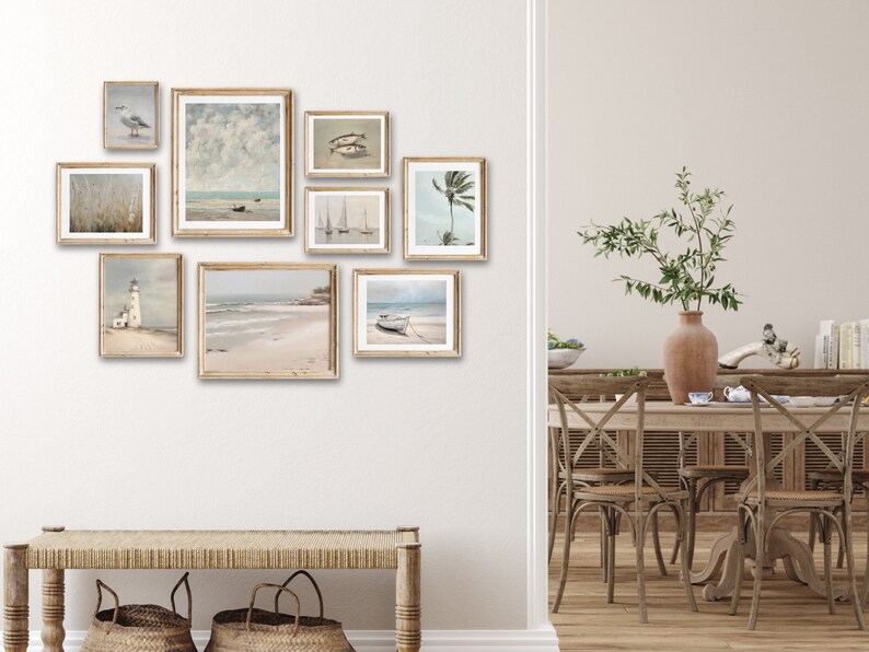 May include: A collection of framed coastal-themed artwork featuring seascapes, lighthouses, and palm trees. The artwork is displayed on a white wall above a wooden bench with woven baskets.