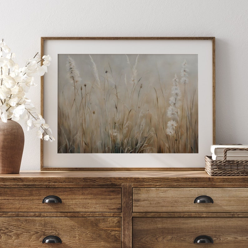 May include: A framed painting of a field of tall grasses and wildflowers in shades of brown, white, and gray. The painting has a soft, dreamy feel.
