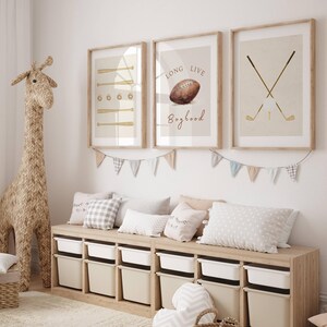 May include: Three framed prints with a sports theme. The first print features a baseball bat and ball, the second print features a football and the text "Long Live Boyhood", and the third print features two golf clubs and a golf ball.