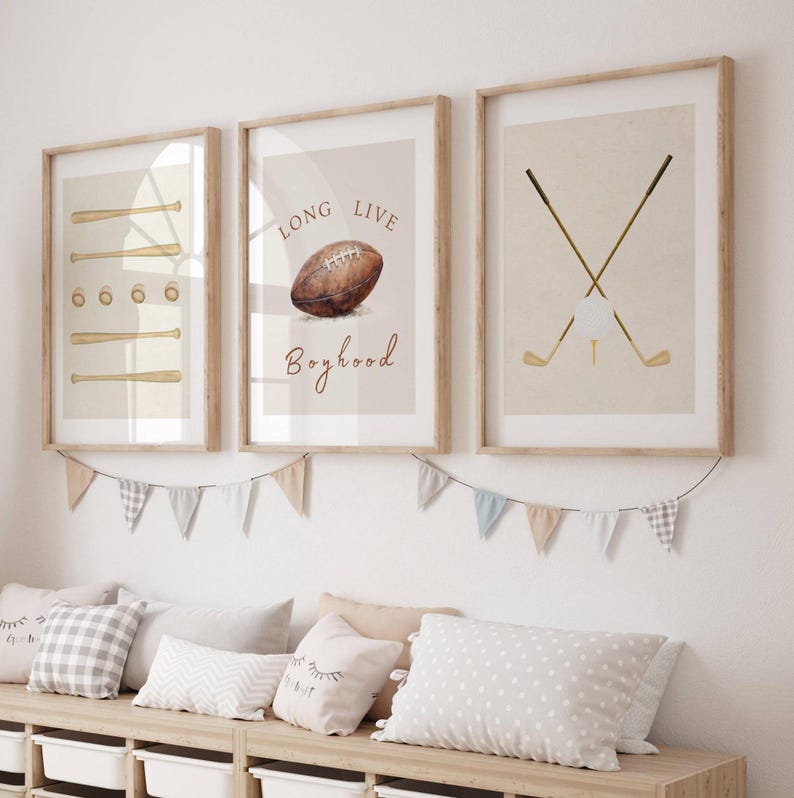 May include: Three framed prints with a sports theme. The first print features a baseball bat and ball, the second print features a football and the text "Long Live Boyhood", and the third print features two crossed golf clubs and a golf ball.