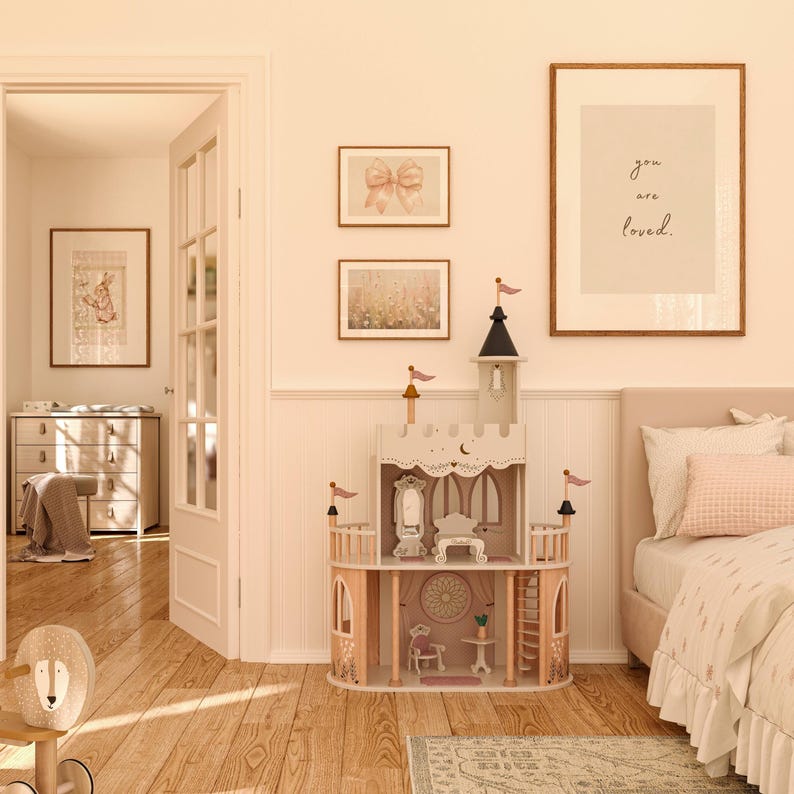 May include: A wooden dollhouse shaped like a castle with a pink and white color scheme. The dollhouse has multiple levels and rooms, including a bedroom, kitchen, and living room. The dollhouse is decorated with small details, such as flags, windows, and a door. The dollhouse is sitting on a wooden floor in a room with a white wall and a white rug. The dollhouse is surrounded by other furniture, including a dresser, a bed, and a chair.