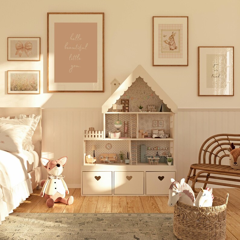 May include: A white dollhouse with a pink and white floral wallpaper interior. The dollhouse has multiple rooms and a ladder. The dollhouse is in a room with a white rug, a white bed, and a white wicker chair. There are several framed prints on the wall, including one that says "hello beautiful little you".